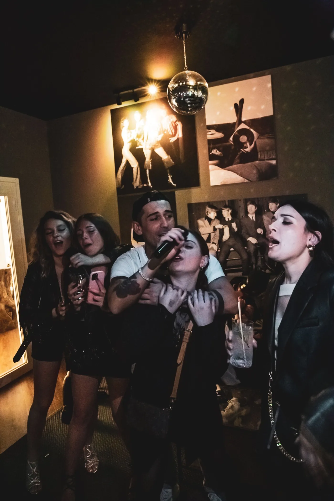 A group hugging around the mic under the mirror ball